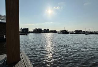 Zonnig uitzicht op het water en woonboten bij Houseboat 'Riggelbrug', Welcome In - Friesland, Nederland.