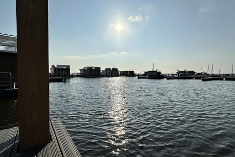 Sonniger Blick auf das Wasser und Hausboote bei Houseboat 'Riggelbrug', Welcome In - Friesland, Niederlande.