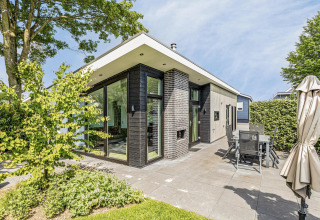 Moderne Natuurlodge aan Recreatiepark het Esmeer in Nederland met grote ramen en gezellige terrasruimte.