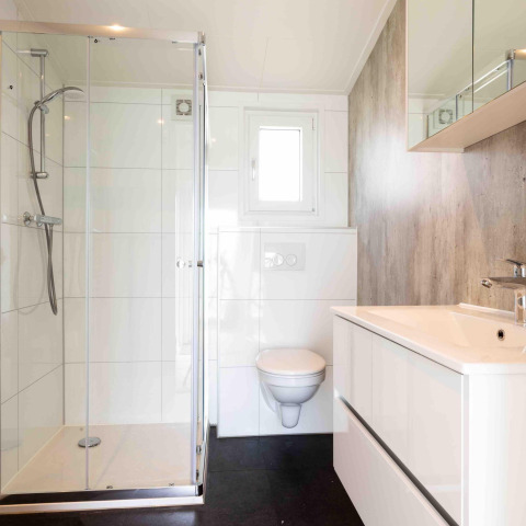 Baño moderno en Natuurlodge, Recreatiepark het Esmeer, Países Bajos, con ducha y sanitario suspendido.
