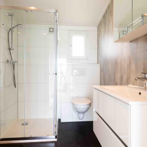 Modern bathroom at Natuurlodge in Recreatiepark het Esmeer, Netherlands, featuring shower and wall toilet.