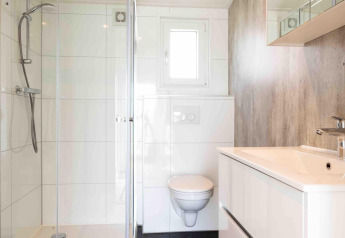 Modernes Badezimmer in der Natuurlodge im Recreatiepark het Esmeer, Niederlande, mit Dusche und WC.