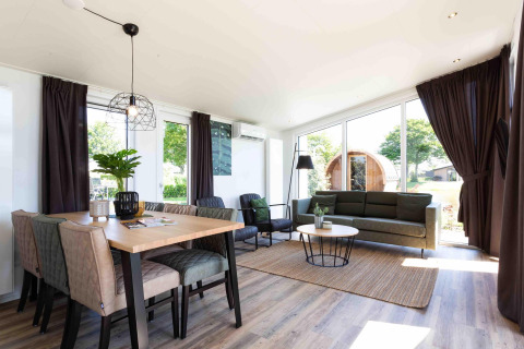 Lyst og moderne opholdsområde i Natuurlodge ved Recreatiepark het Esmeer, med spisebord og udsigt.