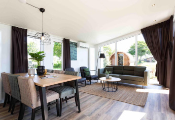 Lyst og moderne opholdsområde i Natuurlodge ved Recreatiepark het Esmeer, med spisebord og udsigt.