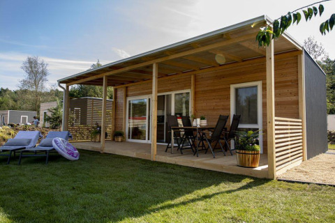 Moderna cabaña Cosy Unique en Maasduinen, Países Bajos, con terraza de madera y muebles de jardín.