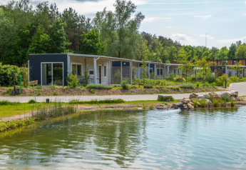 Lodge moderni sul lago a Maasduinen, Paesi Bassi, circondati da vegetazione rigogliosa e natura tranquilla.