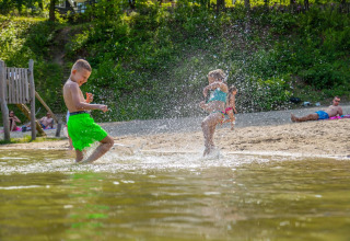 Kinder spielen am Wasser am Cosy Unique at Maasduinen in den Niederlanden an einem sonnigen Tag.