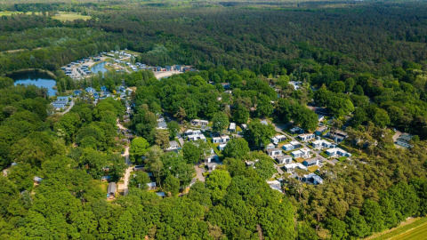 Luchtfoto van Cosy Unique bij Maasduinen in Nederland, omringd door bos en moderne lodges.