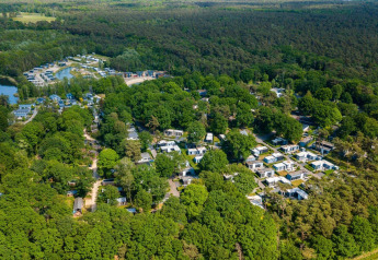 Luftfoto af Cosy Unique ved Maasduinen i Holland, omgivet af grøn skov og moderne lodges.