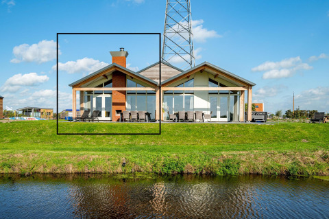 Lodge moderne Anker à Tusken de Marren aux Pays-Bas, grandes baies vitrées et jardin vert près de l’eau.