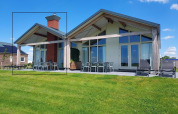 Moderne lodge ved navn Anker ved Tusken de Marren i Holland under en klar blå himmel med grøn græsplæne.