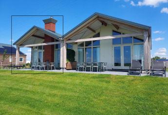 Moderne lodge Anker aan Tusken de Marren in Nederland met een grasveld en heldere blauwe lucht.