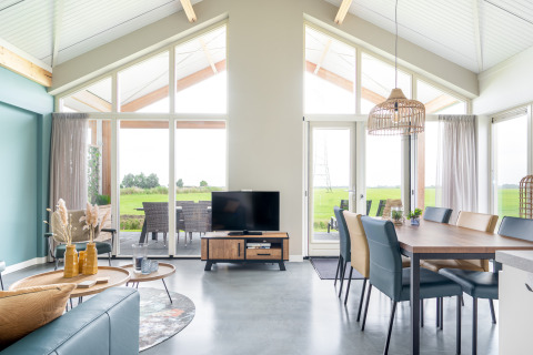 Helles, modernes Wohnzimmer in der Anker-Lodge bei Tusken de Marren, Niederlande, mit Panoramafenstern.