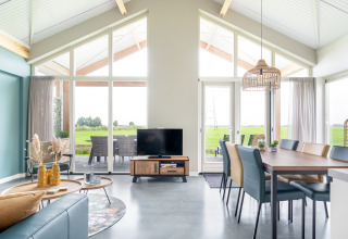 Lichte, moderne leefruimte in de Anker-lodge bij Tusken de Marren, Nederland, met grote ramen en uitzicht.