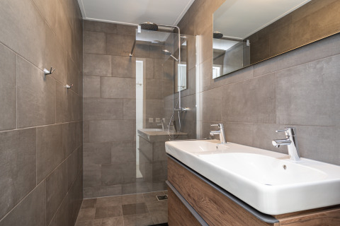 Baño moderno en la cabaña Anker en Tusken de Marren, Países Bajos, con doble lavabo y ducha tipo lluvia.