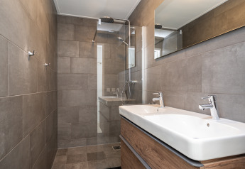 Moderne badkamer in de Anker lodge in Tusken de Marren, Nederland, met dubbele gootsteen en regendouche.