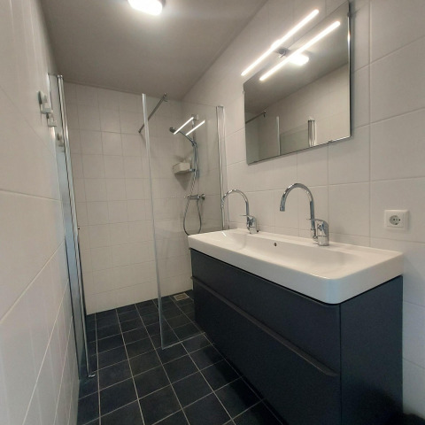 Baño moderno con lavabo doble y ducha de cristal en la cabaña Anker, Tusken de Marren, Países Bajos.