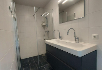 Baño moderno con lavabo doble y ducha de cristal en la cabaña Anker, Tusken de Marren, Países Bajos.