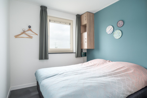 Dormitorio moderno en la cabaña Anker en Tusken de Marren, Países Bajos, con pared azul y decoración.