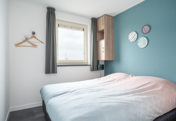 Moderne slaapkamer in de Anker-lodge bij Tusken de Marren, Nederland met blauwe muur en decoratie.