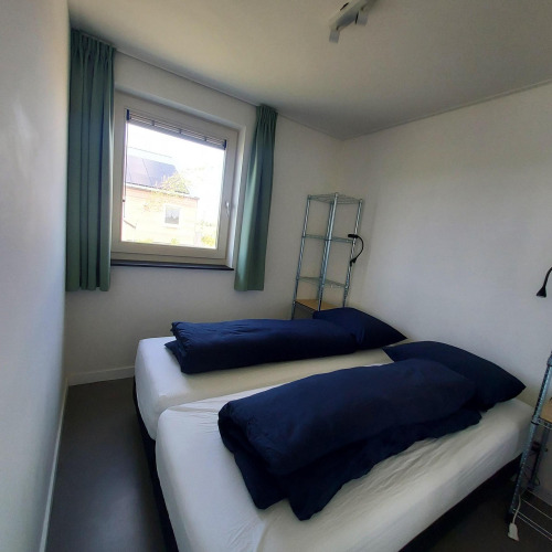 Kleines Zimmer mit zwei Einzelbetten und dunkelblauer Bettwäsche in der Anker-Lodge, Tusken de Marren, Niederlande.
