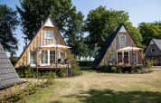 To hyggelige A-formede Wellness Lodge mini-hytter med terrasser og parasoller på Hof van Salland, Holland.