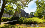 Wellness Lodge tiny house i Hof van Salland, Holland, omgivet af grønne træer og en lille dam.