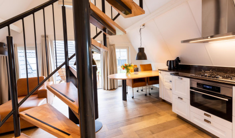 Moderne, kompakt wellness lodge i Hof van Salland, Holland med spiraltrappe og elegant køkkenområde.