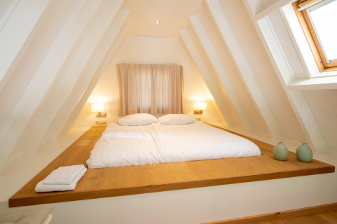 Soveværelse med stor seng og skrå vægge i Wellness Lodge på Hof van Salland, Holland, lyst og hyggeligt.