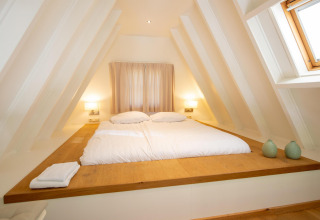 Chambre lumineuse au toit incliné avec grand lit à la Wellness Lodge, Hof van Salland, Pays-Bas.