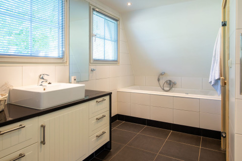 Moderne badeværelse i Wellness Lodge, Hof van Salland, Holland med badekar og hvidt interiør.