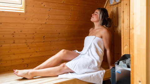 Kvinde slapper af i saunaen i Wellness Lodge, et tiny house på Hof van Salland, Holland.