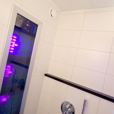 Doccia wellness moderna con illuminazione viola nella tiny house Wellness Lodge presso Hof van Salland, Paesi Bassi.