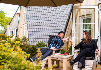 Stel geniet van wijn op het terras van Wellness Lodge bij Hof van Salland in Nederland, zonnige dag.