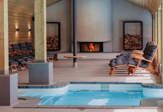 Zona de bienestar interior con piscina, sillones y chimenea en Wellness Lodge, Hof van Salland, Países Bajos.
