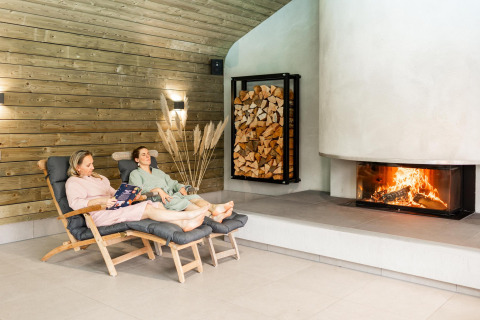 Due persone si rilassano nella Wellness Lodge con camino e legnaia a Hof van Salland, Paesi Bassi.