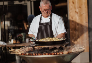 Un chef cocina al aire libre en la parrilla en Wellness Lodge, Hof van Salland, Países Bajos.