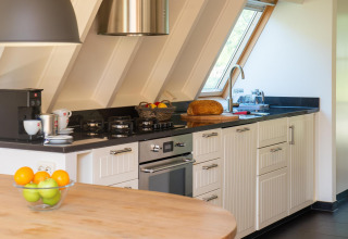 Moderne keuken in Wellness Lodge, Hof van Salland, Nederland, met vers fruit, brood en koffie.