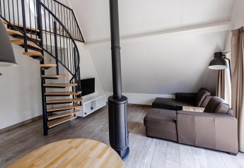 Moderne stue i tiny house Wellness Lodge, Hof van Salland, Holland, med spiraltrappe og lædersofa.