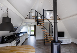 Interior moderno en Wellness Lodge, Hof van Salland, Países Bajos, con escalera de caracol, cocina y altillo.