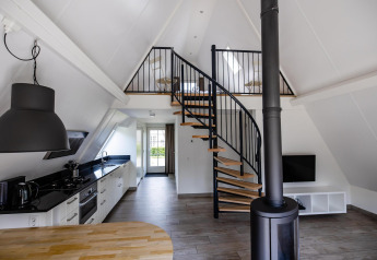 Interior moderno en Wellness Lodge, Hof van Salland, Países Bajos, con escalera de caracol, cocina y altillo.