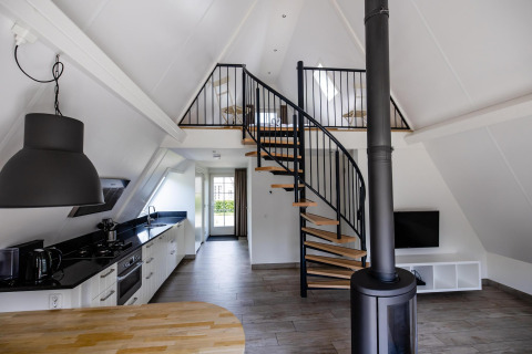 Interni moderni della Wellness Lodge, Hof van Salland, Paesi Bassi, con scala a chiocciola, cucina e soppalco.