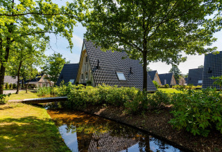 Wellness Lodge au Hof van Salland aux Pays-Bas avec chalets en A, arbres verdoyants et ruisseau calme.