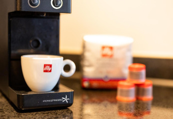 Primer plano de una cafetera illy y taza en una tiny house del Wellness Lodge en Hof van Salland, Países Bajos.