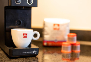 Primer plano de una cafetera illy y taza en una tiny house del Wellness Lodge en Hof van Salland, Países Bajos.