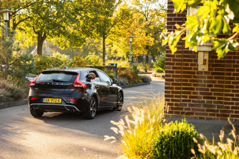 Une Volvo noire avec un chien à la fenêtre passe devant Wellness Lodge à Hof van Salland, Pays-Bas.