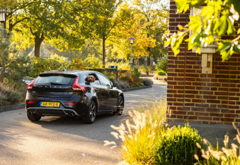 Une Volvo noire avec un chien à la fenêtre passe devant Wellness Lodge à Hof van Salland, Pays-Bas.