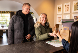 Una pareja se registra en la Wellness Lodge de Hof van Salland en Países Bajos y recibe una bolsa de bienvenida.