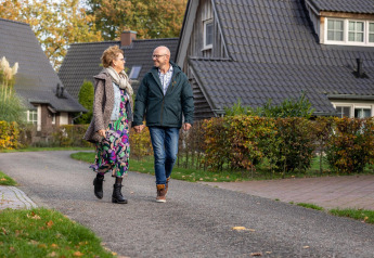 Una coppia anziana passeggia mano nella mano davanti a Wellness Lodge a Hof van Salland, Paesi Bassi.