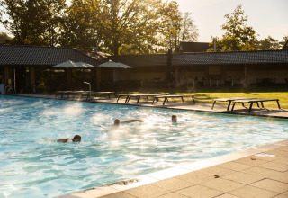 Piscina exterior en Wellness Lodge, Hof van Salland en los Países Bajos, con personas nadando al amanecer.